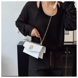 Detail of white handbag featuring woven texture and gold metal M logo and ring handle