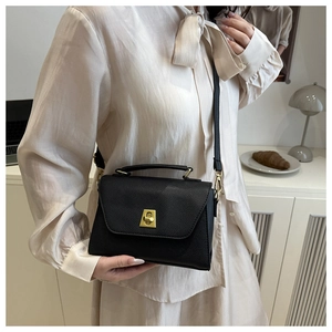 Close-up of black pebble leather crossbody bag with elegant gold metal twist lock