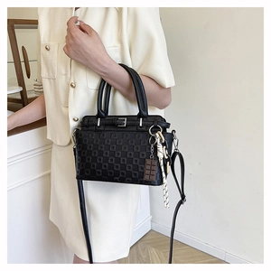 Close-up of black checkered embossed leather tote bag with chocolate charm and strap