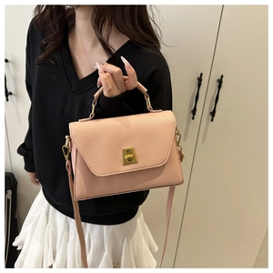 Detail of pink lychee leather texture and golden metal twist lock on a shoulder bag