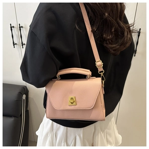 Close-up of pink crossbody bag with litchi texture and gold metal buckle detail