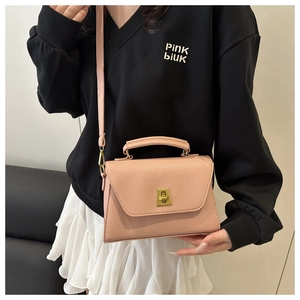 Detailed view of pink textured leather bag featuring elegant gold metal twist lock and handle