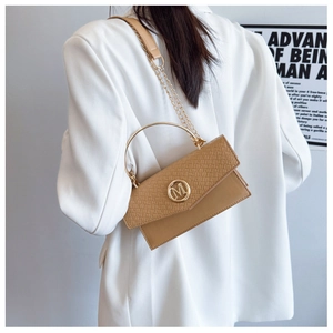 Detail of khaki woven texture handbag with golden M logo and chain strap on model