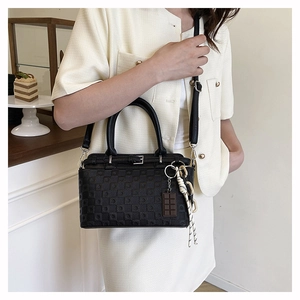 Detail of black checkered handbag featuring a cute chocolate charm and woven tassel accent