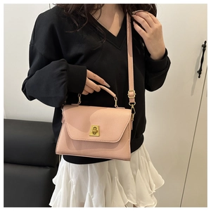 Pink crossbody bag with gold lock buckle and top handle shown on a female model