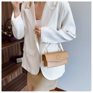 Detail of woven texture flap and golden M logo on light brown crossbody bag