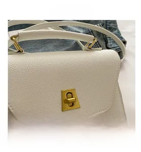 Close-up of white lychee texture leather bag with elegant golden square twist lock