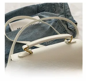 Close-up of white lychee textured bag featuring round handle and gold metal twist lock