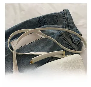 Detail of white lychee grain leather handbag with golden twist lock on denim background
