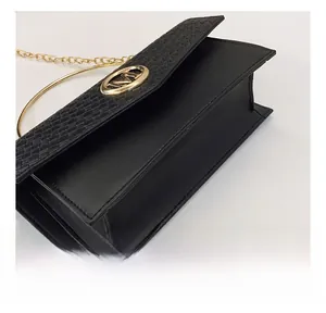 Detail of black woven texture flap and golden M logo on the elegant chain shoulder bag