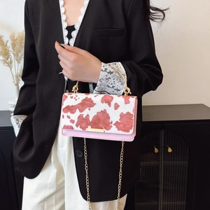 Pink and white cow print rectangular handbag with gold metal handle and chain strap