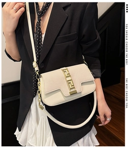 Detail of white canvas and leather saddle bag with golden Greek fret buckle detail