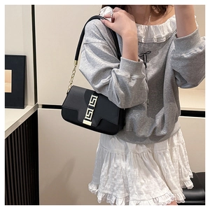 Detail of black leather saddle bag featuring a gold Greca buckle and chain strap