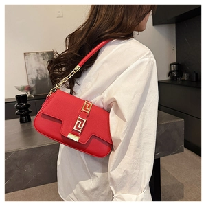 Detail of red leather saddle bag with gold geometric buckle and chain on white shirt