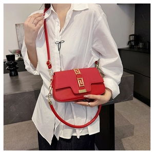 Close-up of a stylish red crossbody saddle bag with a golden geometric metal buckle