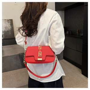 Detail of red leather saddle bag featuring a Greek fret pattern gold metal buckle