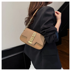 Detail of tan leather saddle bag with gold Greek key buckle and metal chain strap