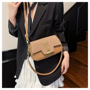 Detailed view of brown textured fabric and leather saddle bag with gold geometric clasp
