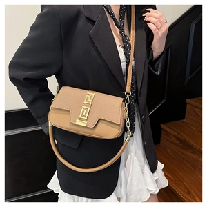Detail of brown saddle bag with golden geometric clasp and textured flap for women