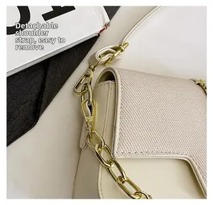 Detail of the golden detachable strap metal clasp on a cream saddle bag leather texture