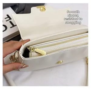 Detail shot of smooth metal zipper and internal compartment on white leather saddle bag