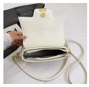 Detail of white saddle bag interior showing zipper pocket and gold metal hardware