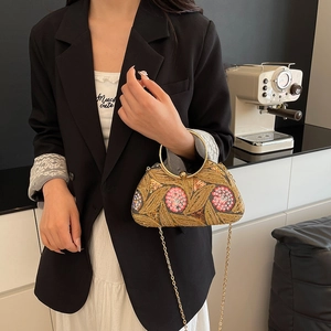 Retro evening bag with golden floral embroidery and metal ring handle held by model