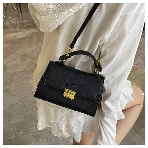 Detail of black pebbled leather crossbody bag with elegant gold square metal buckle