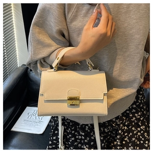 Close-up of white lychee pattern crossbody bag with golden metal buckle and top handle