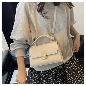 Detailed macro view of the cream leather texture and golden metal lock on the handbag
