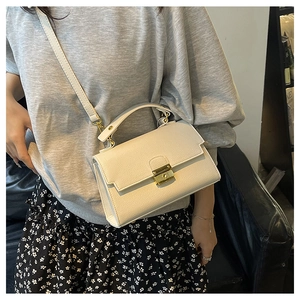 Detail of off-white lychee grain leather handbag with gold metal lock and shoulder strap