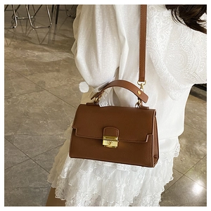 Detail of caramel brown leather handbag with gold metal clasp and textured surface