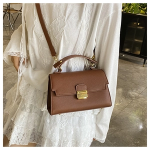 Close-up of brown litchi texture leather handbag with golden buckle and crossbody strap