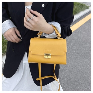 Close-up of vibrant yellow crossbody bag featuring pebble leather texture and gold lock