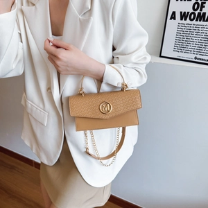 Brown woven texture handbag with golden M logo and metal top handle shown on white suit