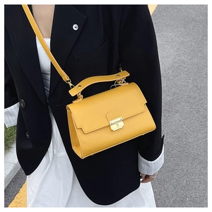 Close-up of bright yellow leather handbag with gold clasp and adjustable strap
