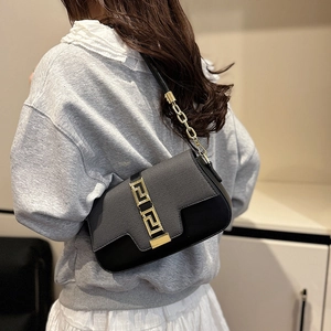 Chic black saddle bag with Greek meander gold buckle shown on shoulder for daily style