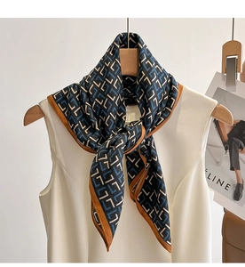 Détail d'un foulard en soie avec motif géométrique en L noué sur une robe blanche élégante
