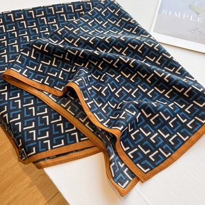 Détail du foulard à motifs géométriques bleus et beiges avec bordure orange élégante