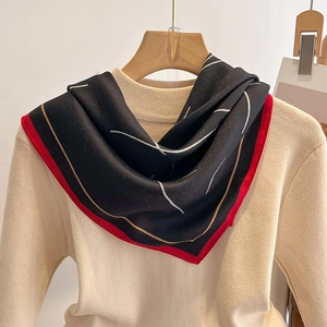 Détail d'un carré de soie noir et rouge élégant avec lignes abstraites sur un pull beige