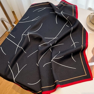 Détail d'un élégant carré en soie noire avec bords rouges et lignes abstraites