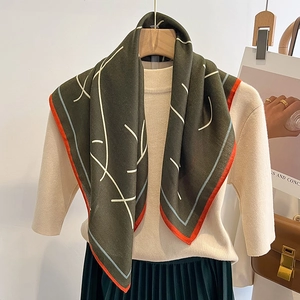 Foulard en soie vert olive avec lignes abstraites et bordures sur tricot beige