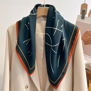 Élégante écharpe en soie vert émeraude à lignes abstraites sur un blazer beige