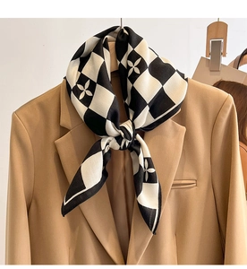Détail d'un foulard en soie à damier avec motifs floraux sur un blazer de couleur camel