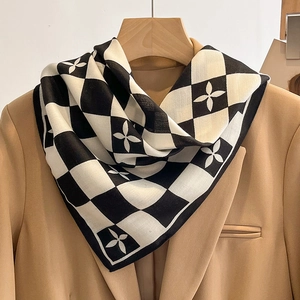 Carré de soie classique à damier et motifs floraux porté sur un blazer camel