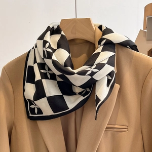 Détail d'un foulard en soie à damier avec motifs trèfles et texture à chevrons sur col