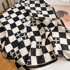 Détail d'une écharpe en maille à damier avec motif floral et texture douce en laine