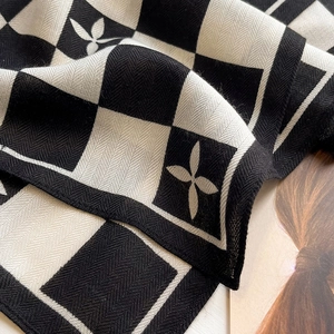Gros plan d'une écharpe à damier montrant le tissage à chevrons et le motif floral