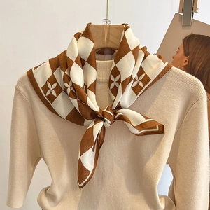 Foulard en soie à carreaux et fleurs noué sur un pull en maille beige chic