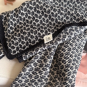 Close-up of pleated cotton linen scarf with black and white texture and fabric label